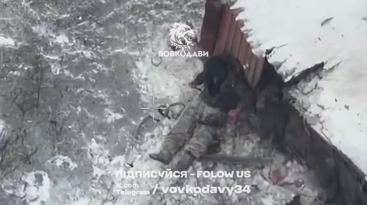 Unequipped and presumably injured Russian soldier is seen sitting besides some kind of ruin, he seems to be stabbing himself in the belly or chest. It's unclear how committed is he, although there appears to be blood on the blade