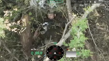 Russian is hiding under heavy foliage facing up, makes eye contact with the drone that films him, proceeds to detonate grenade on his chest